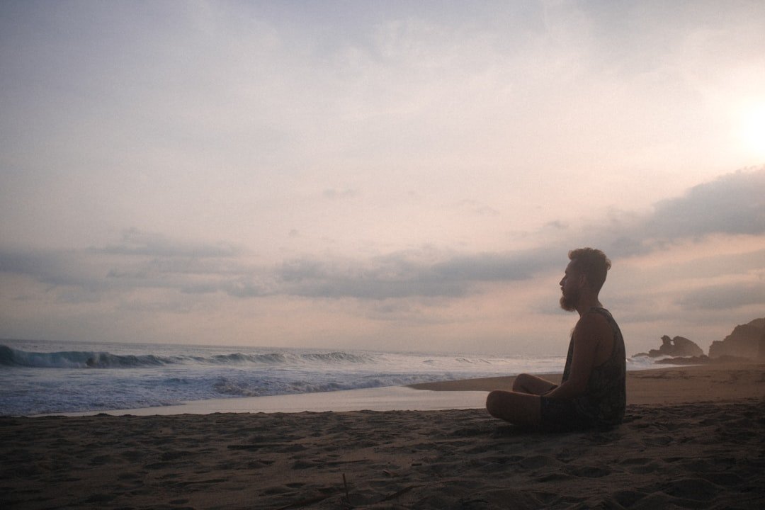 person meditating on the beach at sunset before a surf yoga retreat session